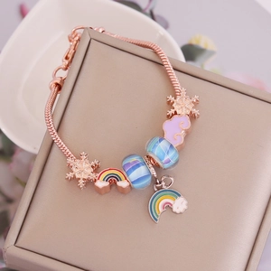 Close-up of rose gold charm bracelet with blue glass beads and enamel rainbow charms