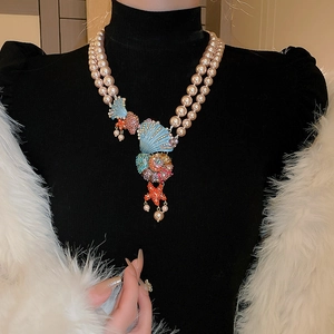 Detail of double-layer pearl necklace with blue shell, starfish and zircon pendants