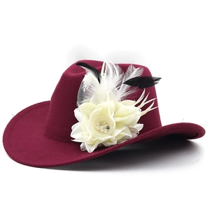 Detail of burgundy wool fedora with white flower, feathers, and rhinestone accents