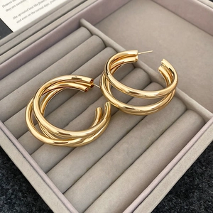 Detailed close-up of triple-layered gold C-shaped hoop earrings on a velvet tray
