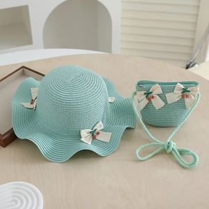 Détail d'un ensemble chapeau et sac en paille vert menthe avec nœuds et cerises