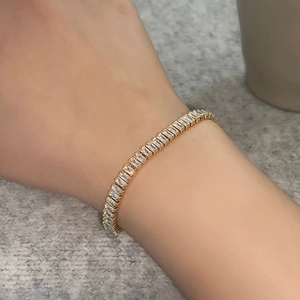Close-up of gold-plated tennis bracelet featuring baguette-cut zircon stones on a wrist