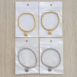 Detail view of gold and silver beaded bracelets with heart charms in retail packaging