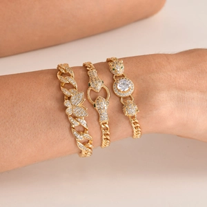 Close-up of stacked gold-tone bracelets featuring pavé cubic zirconia and leopard head motif