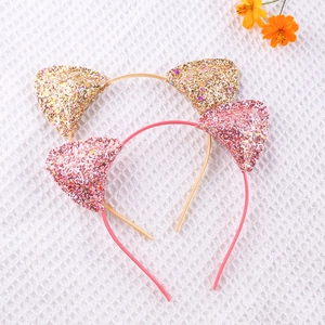 Detail of pink and gold glitter cat ear headbands on a white textured background