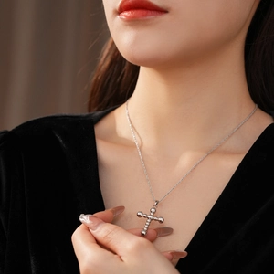 Gros plan détaillé d'un collier pendentif croix argenté sur le cou d'une femme élégant