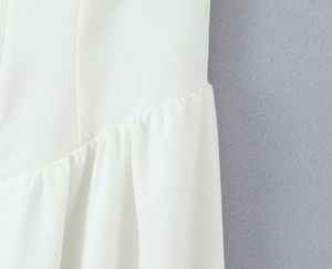 Close-up of white dress fabric showing vertical stitching and ruffle details on material