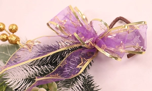 Detail of purple organza ribbon with gold stars on pine branch for Christmas decor