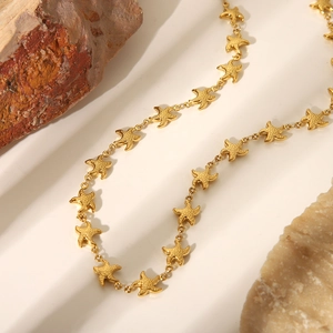 Dettaglio di una lunga collana dorata con ciondoli a forma di stella marina su rocce