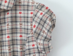 Detail of puff sleeves on a plaid shirt with cute red hearts and brown bear patterns