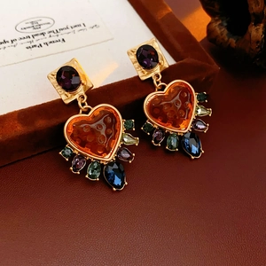 Close-up of vintage heart earrings with colorful crystal accents and golden details