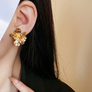 Detail shot of vintage gold flower stud earring with hammered metallic texture on model