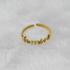 Macro detail of custom gold stainless steel ring with Evelin script on plush background