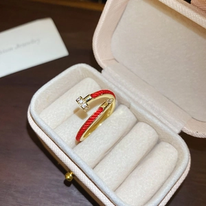 Detail of a gold nail-shaped ring with red woven texture and sparkling zircon inlay
