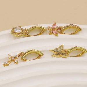 Detailed macro view of gold-plated butterfly and cross charms with white cubic zirconia