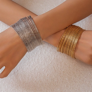 Dettaglio di bracciali rigidi multistrato in oro e argento con finitura diamantata sulle braccia