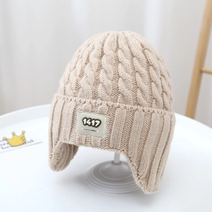 Detailed cable knit texture and embroidered logo patch on a cozy winter earflap hat