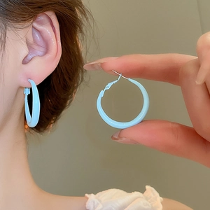 Detail showing smooth light blue hoop earring with silver needle on ear and in hand