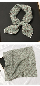 Vue détaillée d'un foulard en soie à fleurs vertes montrant le tissu doux et l'ourlet