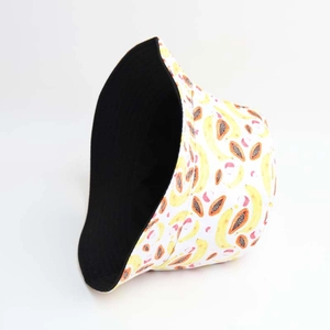 Detail of reversible bucket hat with tropical fruit banana and papaya patterns on black