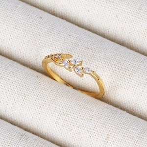 Macro detail of 18K gold leaf ring with marquise cut zircon stones on fabric