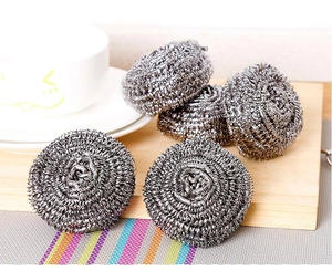 Detail of five silver stainless steel scouring pads on a wooden tray for kitchen cleaning