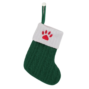 Detail of green knitted Christmas stocking featuring red paw print embroidery on white cuff