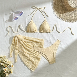 Detailed flat lay of a 3-piece solid cream bikini set with mesh sarong and rib texture