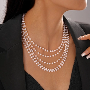 Close-up of elegant multi-layer faux pearl necklace on model with black suit