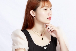 Detailed view of model wearing gold layered necklace with burgundy and black circle charms