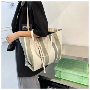 Detail of grey and white striped canvas tote bag with premium leather shoulder straps