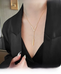 Detail of a gold V-shaped titanium steel necklace with a vertical bar pendant on model