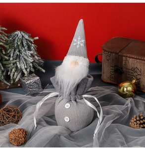 Detail of grey knitted Christmas gnome candy bag with white beard on festive background