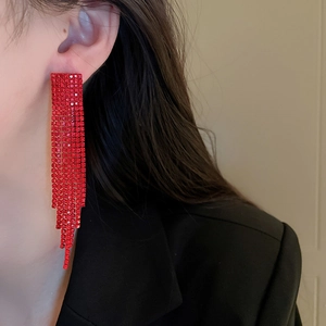 Close-up of sparkling long red tassel earrings with crystal rhinestones on a model