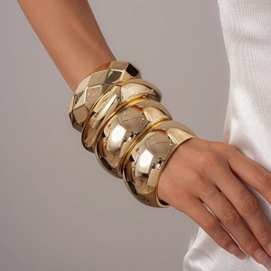 Macro shot of layered gold acrylic chunky bangles with polished geometric faceted surfaces