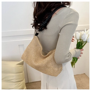 Detail of hand-woven straw hobo bag in khaki with a stylish black leather knotted strap