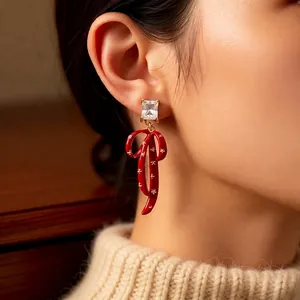 Elegant red enamel bow earrings with square zircon stone shown on a female model