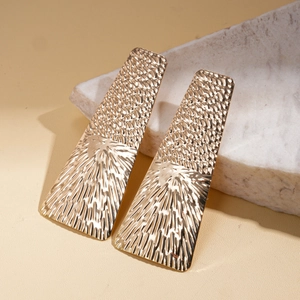 Detail of gold geometric square earrings with textured dots and radiant line patterns