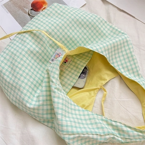 Macro view of green plaid tote bag showing bright yellow lining and internal pocket