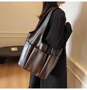 Side view of dark brown large capacity faux leather tote bag with three front pockets