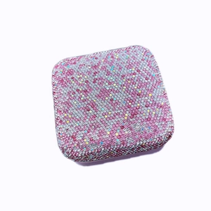 Close-up of a portable jewelry box covered in sparkling pink and iridescent rhinestones