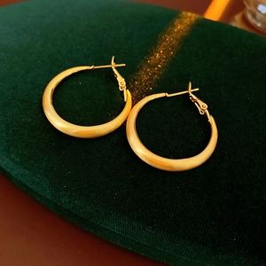 Close-up of golden geometric round hoop earrings with matte texture on velvet box