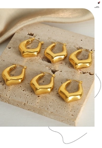 Detail of three pairs of V-shaped gold plated geometric earrings on a beige stone display