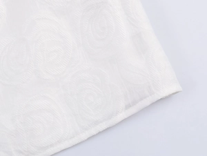 Close-up of white textured floral pattern fabric with elegant embroidered swirl details
