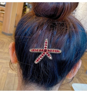 Close-up of a sparkling red starfish hair clip with rhinestones on a stylish bun