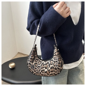 Close-up of stylish leopard print crescent bag worn by a model in a minimal setting