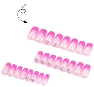 Detail of pink gradient press-on nails with 3D embossed flower patterns and tiny rhinestones