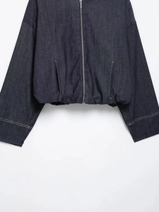 Detail of dark blue denim bomber jacket with contrast stitching and metal zipper closure