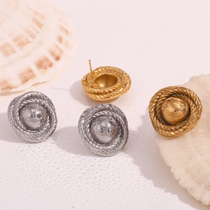 Close-up of gold and silver twisted button earrings with water droplets on shells
