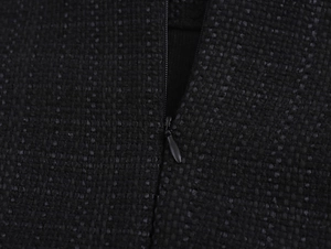 Dettaglio della trama del tessuto in tweed nero e della cerniera invisibile piatta